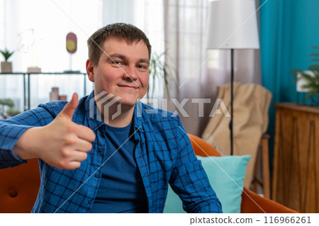 Excited Caucasian man looking approvingly at camera showing thumbs up like sign satisfied feedback 116966261
