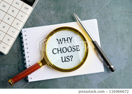 Why choose us symbol. Business motivational . Copy space. Words WHY CHOOSE US through the lens of a magnifying glass in a notebook on a gray background 116966672