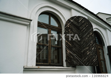 An old, vintage building with a door on the windows 116966824