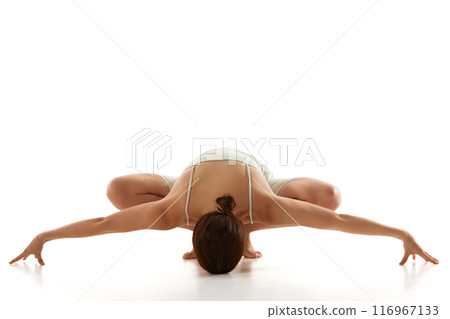 Woman enhances her flexibility and body awareness during, stretching, yoga session against white studio background. 116967133