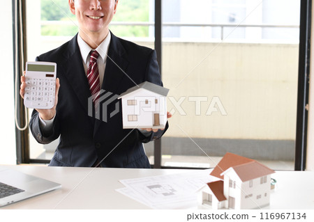 Young Asian man in a suit holding a house model and a calculator 116967134