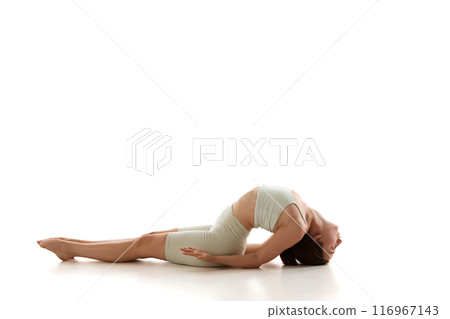 Fit woman in athletic wear engages in fish pose, focusing on opening her chest and improving spinal flexibility against white background. 116967143