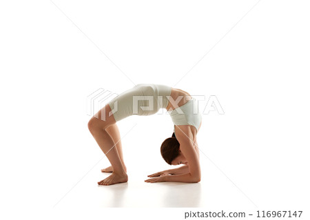 Woman practices forearm wheel pose, enhancing her back strength against white studio background. Yoga training and overall physical resilience. 116967147