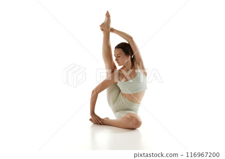 Woman during stretching practice, focusing on flexibility and balance, components of her comprehensive yoga training and overall physical well-being. 116967200