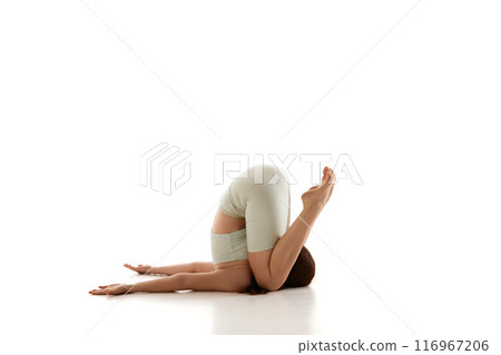Woman practices Plow pose, enhancing spinal flexibility and promoting relaxation. Training physical and mental wellness against white studio background. 116967206