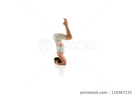 Woman enhances her stability and focus, during yoga session against white studio background. Strength and mental clarity. 116967235