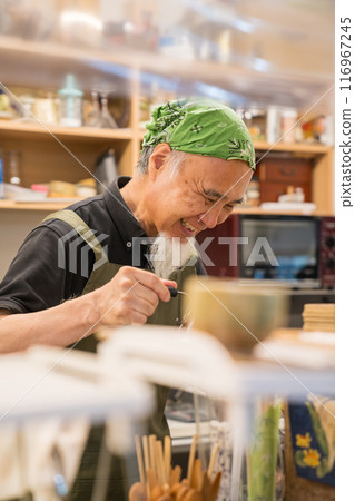A man in his 60s is pursuing a fulfilling second career as a cafe owner after retirement 116967245