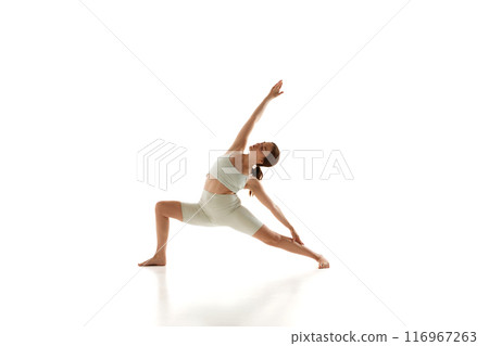 Woman in athletic wear performs yoga pose, stretching her legs, arms and back against white studio background. Healthy lifestyle. 116967263