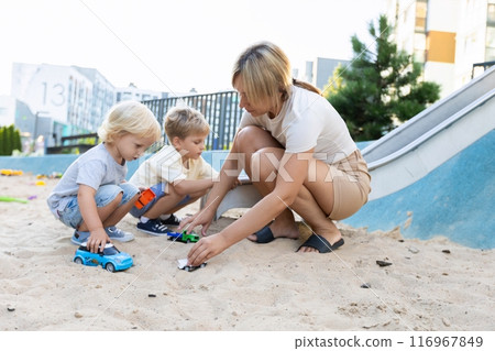 Mother Engaging in Playtime With Two Sons in a Vibrant Playground During Sunny Weather 116967849