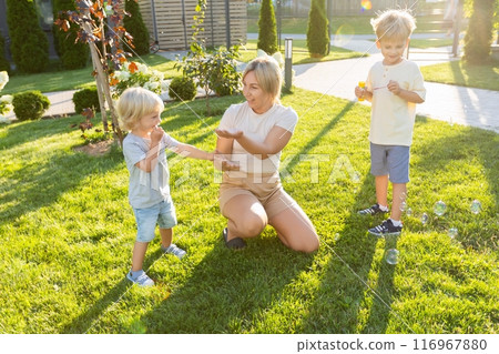 Mother Playing With Her Two Sons in a Sunny Playground Garden in the Afternoon Mother Playing With Her Two Sons in a Sunny Playground Garden in the Afternoon 116967880