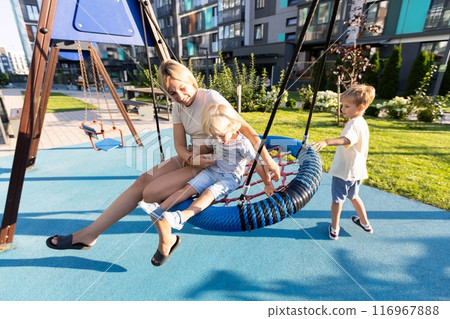 Mother Enjoys Quality Time With Her Two Sons on a Sunny Playground Swing Mother Enjoys Quality Time With Her Two Sons on a Sunny Playground Swing 116967888