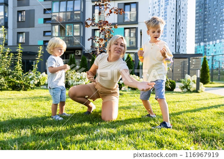 Mother Enjoying Quality Time With Her Two Sons in a Playground Setting on a Sunny Day 116967919