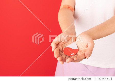 Blood donation. Blood donor holding blood drop shape over red background. Concept of world blood donor day, anemia, sickle cell disease, hemophilia, leukemia and ITP. Blood donation. Blood donor holding blood drop shape over red background. Concept of world blood donor day, anemia, sickle cell disease, hemophilia, leukemia and ITP. 116968391