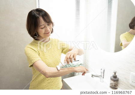 A woman's hands depilating her arms in the bathroom 116968767