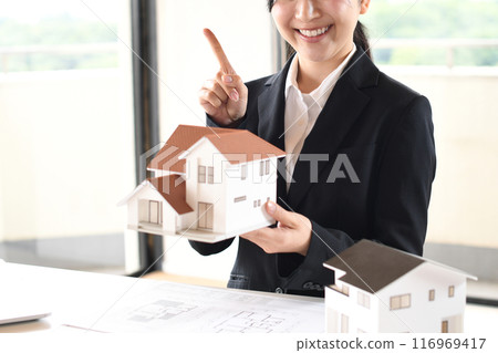 一位女上班族拿著房屋模型，揮舞著食指 116969417