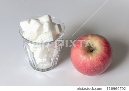 Full glass of sugar and red apple. 116969702