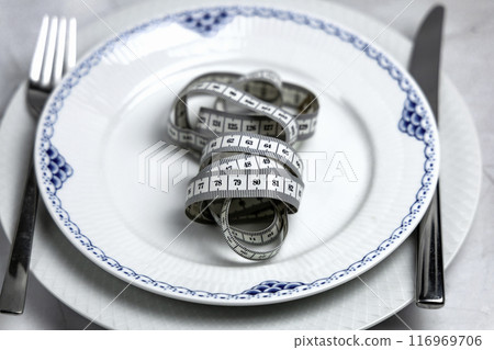 Concept of healthy eating and weight loss. Plate with measuring tape. 116969706
