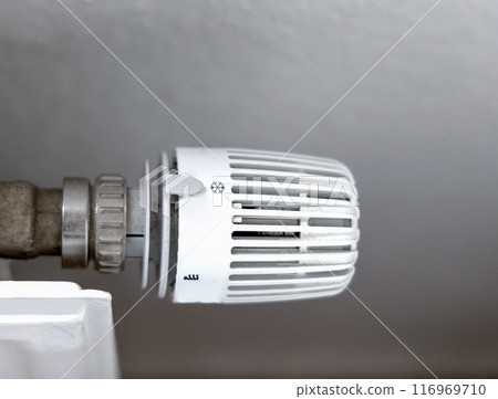 Heating battery temperature regulation in house with thermostat on white radiator. 116969710