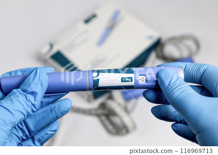 Hands in surgical gloves holding Ozempic Insulin injection pen for diabetics. 116969713
