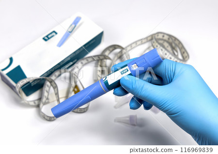 Hands in surgical gloves holding Ozempic Insulin injection pen for diabetics. 116969839