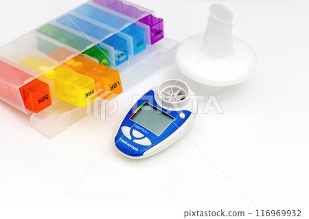 Tablets in a dispenser and peak flow meter on a white background. 116969932