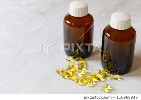 Medicine bottle of brown glass and yellow capsules with food supplement omega three. 116969939