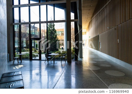 Hall in a modern building with large glass windows and a sitting area. 116969940
