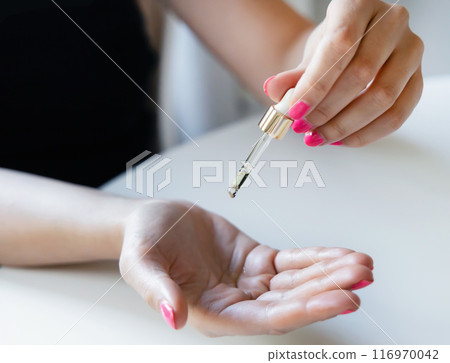 Female hands with a pipette with oil for hair or facial care. Female hands with a pipette with oil for hair or facial care. 116970042