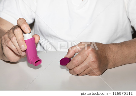 Man holding asthma inhaler in his hands. 116970111