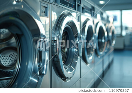 A row of industrial washing machines in a public laundromat 116970267