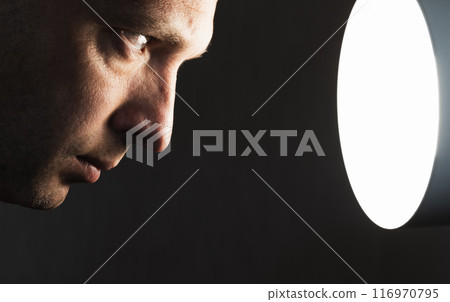 Close up profile portrait of young man staring at the light Close up profile portrait of young man staring at the light 116970795