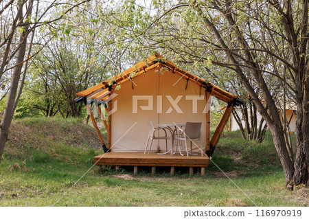 Cozy open glamping tents with light inside in summer camp. Camping tent for holiday and vacation Cozy open glamping tents with light inside in summer camp. Camping tent for holiday and vacation 116970919