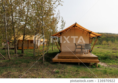 Cozy open glamping tents with light inside in summer camp. Camping tent for holiday and vacation 116970922