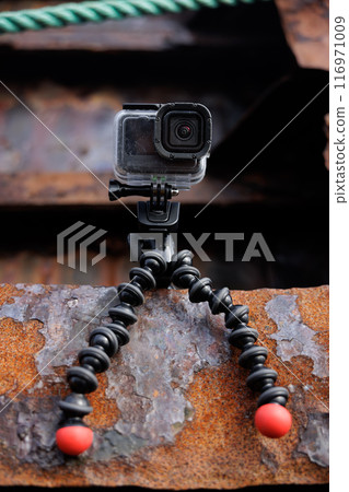 Closeup of action camera attached to a rough, rusty surface 116971009