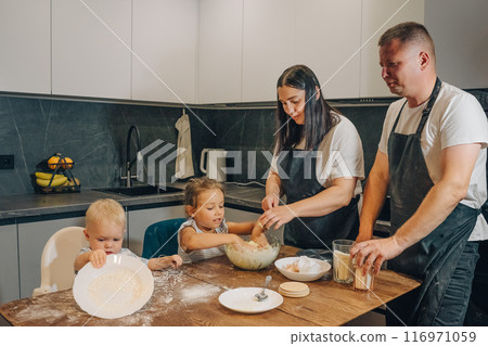 A Joyful Family Enjoys Baking Together in Their Cozy Kitchen, Creating Delicious Treats. Happy family enjoys moments of cooking at home. A Joyful Family Enjoys Baking Together in Their Cozy Kitchen, Creating Delicious Treats. Happy family enjoys moments of cooking at home. 116971059