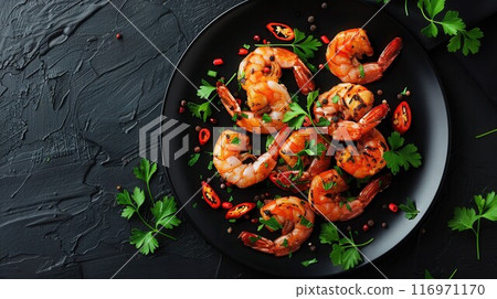 Grilled tiger prawns in white plate with spices on vintage black background, top view, copy space. Stone kitchen table with seafood dinner 116971170