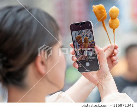 Woman taking a photo with her smartphone Osaka city Kushikatsu 116971341