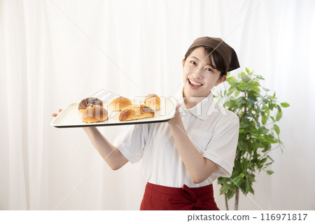 Female bakery staff holding freshly baked bread Female bakery staff holding freshly baked bread 116971817