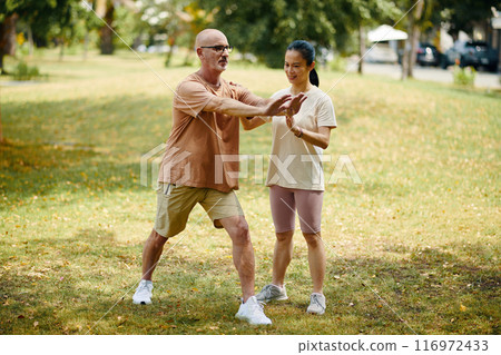 Exercising Outdoors with Fitness Coach in Morning Park Setting 116972433
