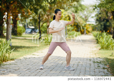 Practicing Tai Chi in Garden Pathway on Sunny Day Practicing Tai Chi in Garden Pathway on Sunny Day 116972441