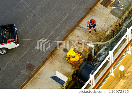 The process of mooring a large ship at the harbor pier, pulling the rope ashore using a pickup The process of mooring a large ship at the harbor pier, pulling the rope ashore using a pickup 116972835
