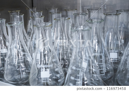 Glass Erlenmeyer flasks on the shelf ready for chemical analysis.  116973458