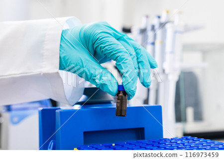 A chemist uses a vortex mixer to shake samples before HPLC analysis 116973459