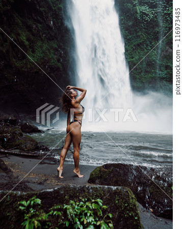 Gorgeous woman in bikini near waterfall in Bali. 116973485