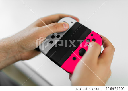 Man playing video games in living room sitting on sofa. 116974301