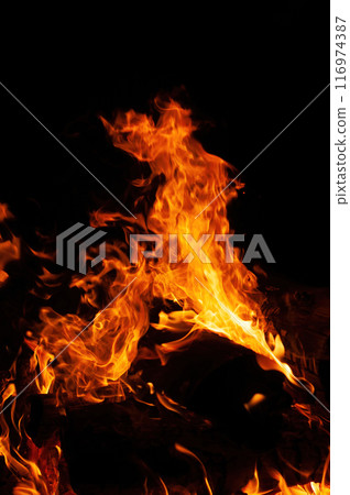 Close up of a bonfire blazing with intense heat against a Close up of a bonfire blazing with intense heat against a 116974387