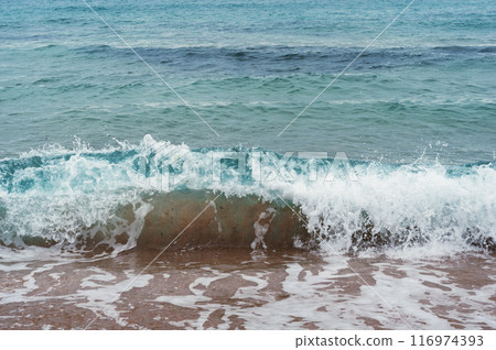 Crystal-clear turquoise waves gently break on the shore 116974393