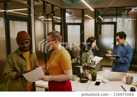 Multi-ethnic group of young men and women wearing stylish casual clothes working in pairs in modern office Multi-ethnic group of young men and women wearing stylish casual clothes working in pairs in modern office 116975089