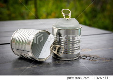 Twp empty and opened cans on wooden table Twp empty and opened cans on wooden table 116975118