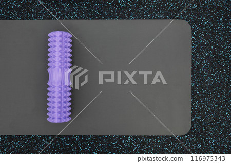 Foam roller and exercising mat on sports ground for training. Outdoor workout. Ready for morning routine. Copy space. View from above. Healthy lifestyle. 116975343